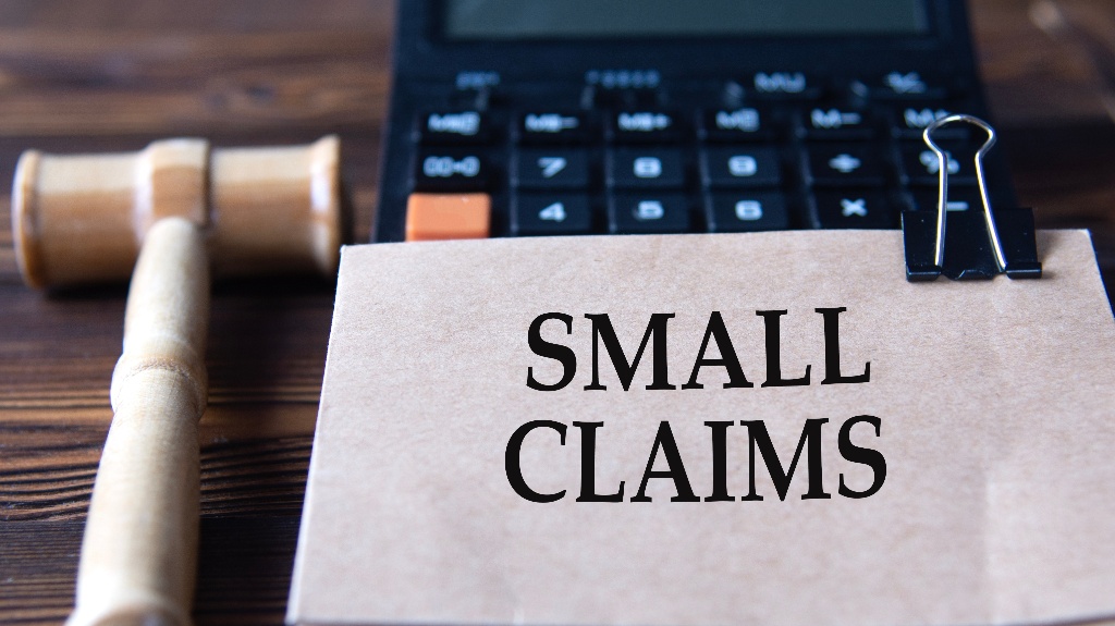 SMALL CLAIMS - words on paper against the background of a calculator and a judge's gavel
