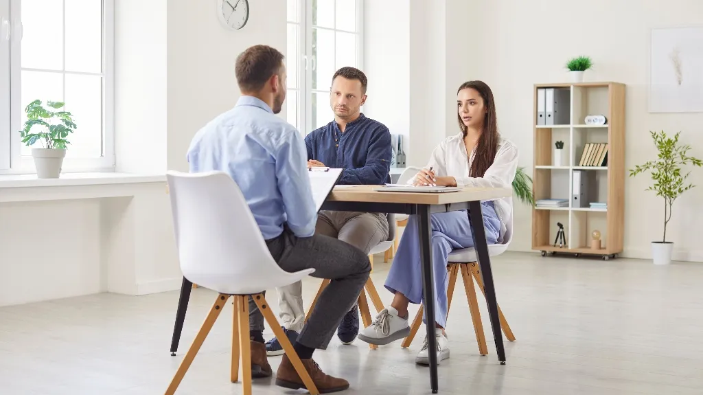 Three professionals engaged in a formal meeting in a bright, modern office setting.