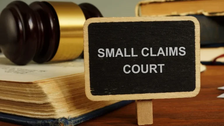 Small wooden sign with "Small Claims Court" text beside a judge's gavel and legal books.