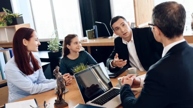 Four people, including a young girl and three adults, engaged in a business meeting around a wooden table.