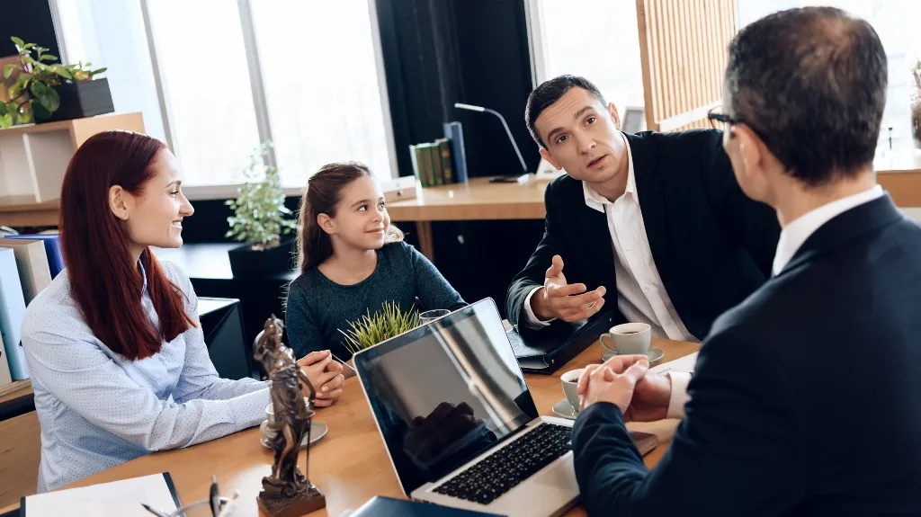 Four people, including a young girl and three adults, engaged in a business meeting around a wooden table.