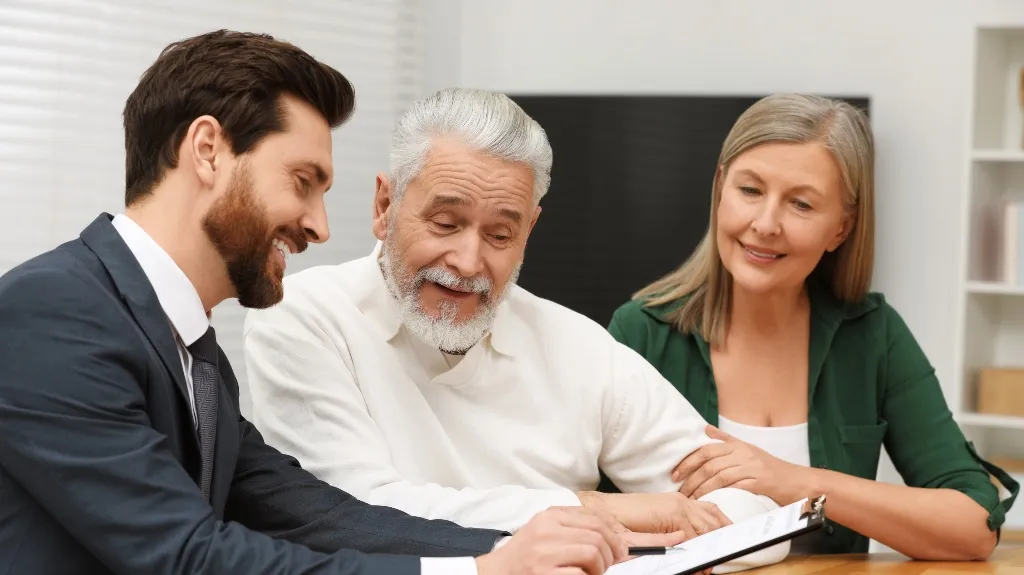 Three adults, two men and one woman, reviewing documents together at a table.